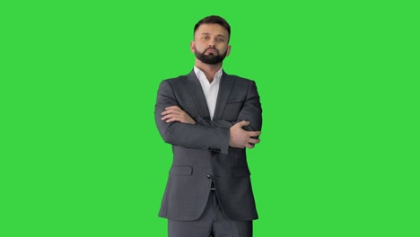 confident business man with beard and mustashes in suit standing with folded hands on a green screen, chroma key