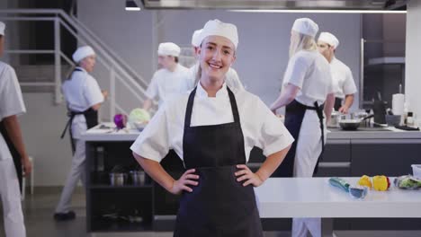 cocinera caucásica trabajando en la cocina de un restaurante mirando a la cámara y sonriendo