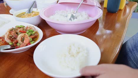 hands serving rice from a communal bowl to plates