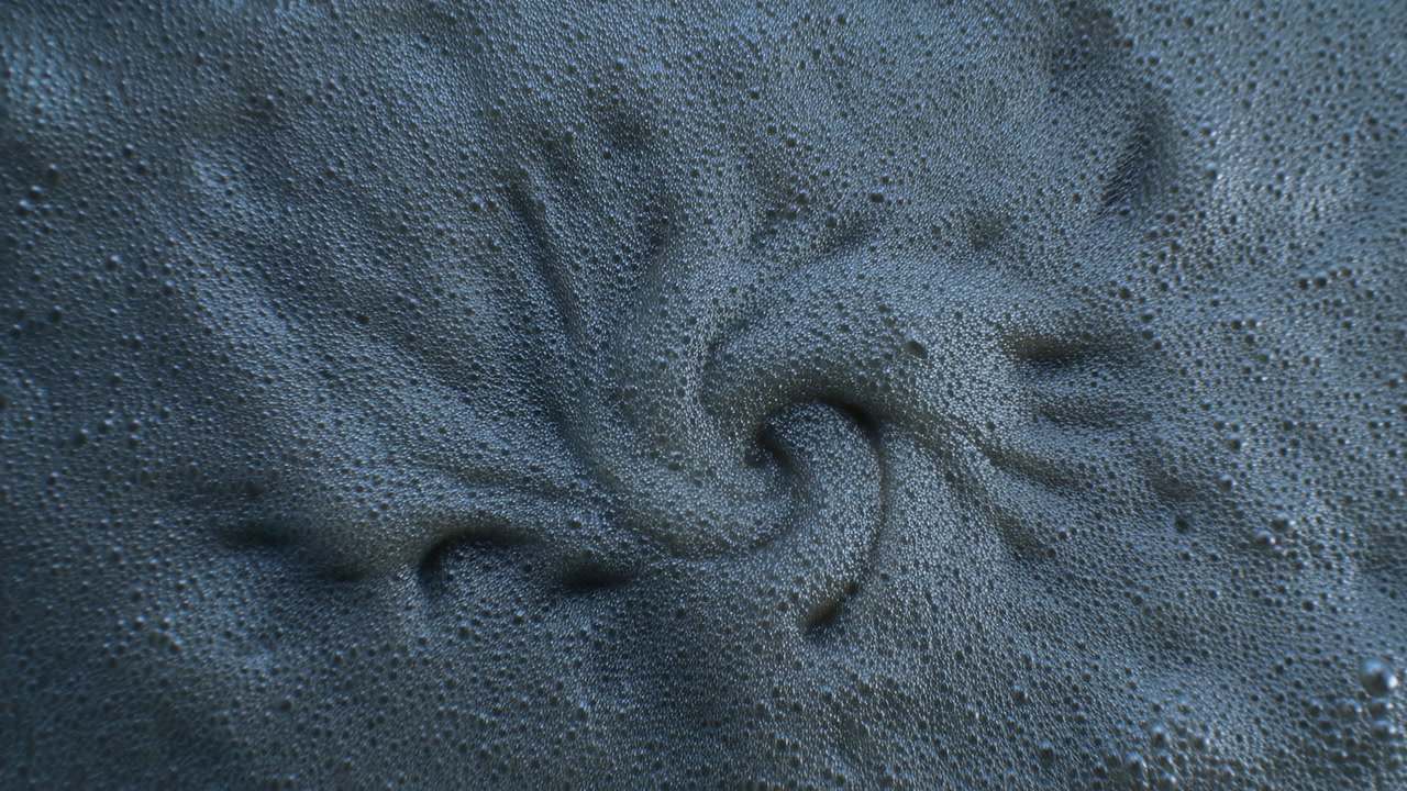 Closeup Swirling Foam Vortex On Surface, Dense Bubbly Texture In Dark Blue Tone, Central Whirlpool Depression