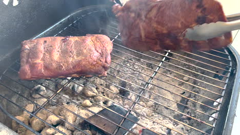 costillas de cerdo asadas a la parrilla de carbón caliente, volteadas con pinzas