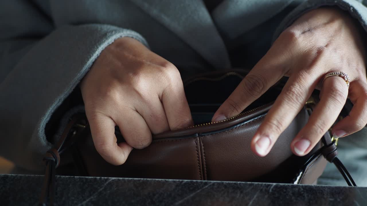 mujer abriendo un bolso de cuero marrón