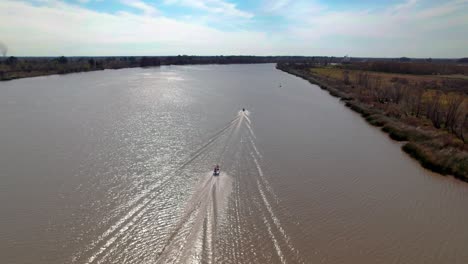 Motorboats-creating-wakes-on-river---aerial-view