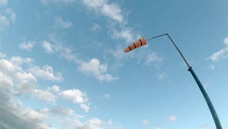 Gestreifter-Flughafenwindsack-In-Zeitlupe,-Der-Gegen-Den-Blauen-Bewölkten-Himmel-Weht-Und-Nach-Oben-Schaut