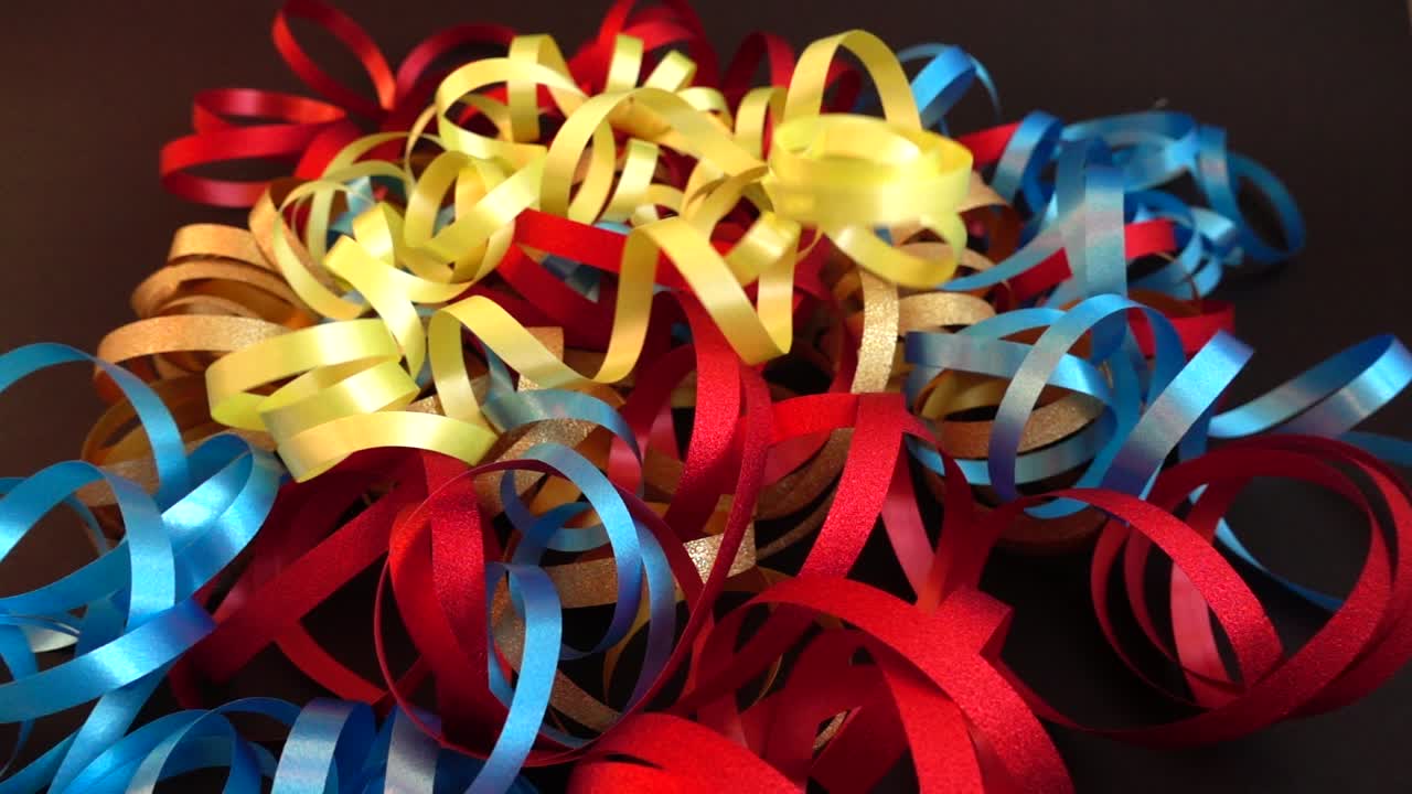 Cintas amarillas cayendo sobre una pila de serpentinas de fiesta coloridas