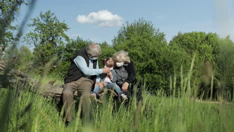 grandparents with granddaughter in medical masks in park. coronavirus quarantine