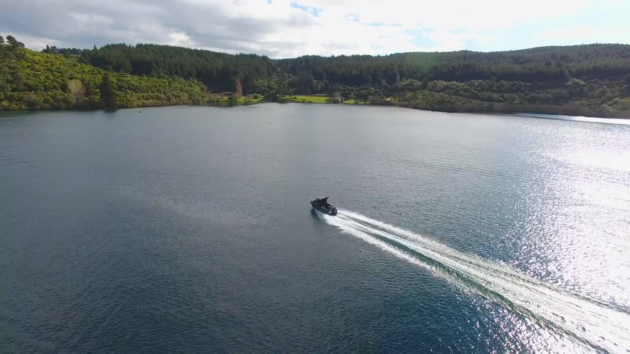 A boat cruising on a lake with a forested shoreline