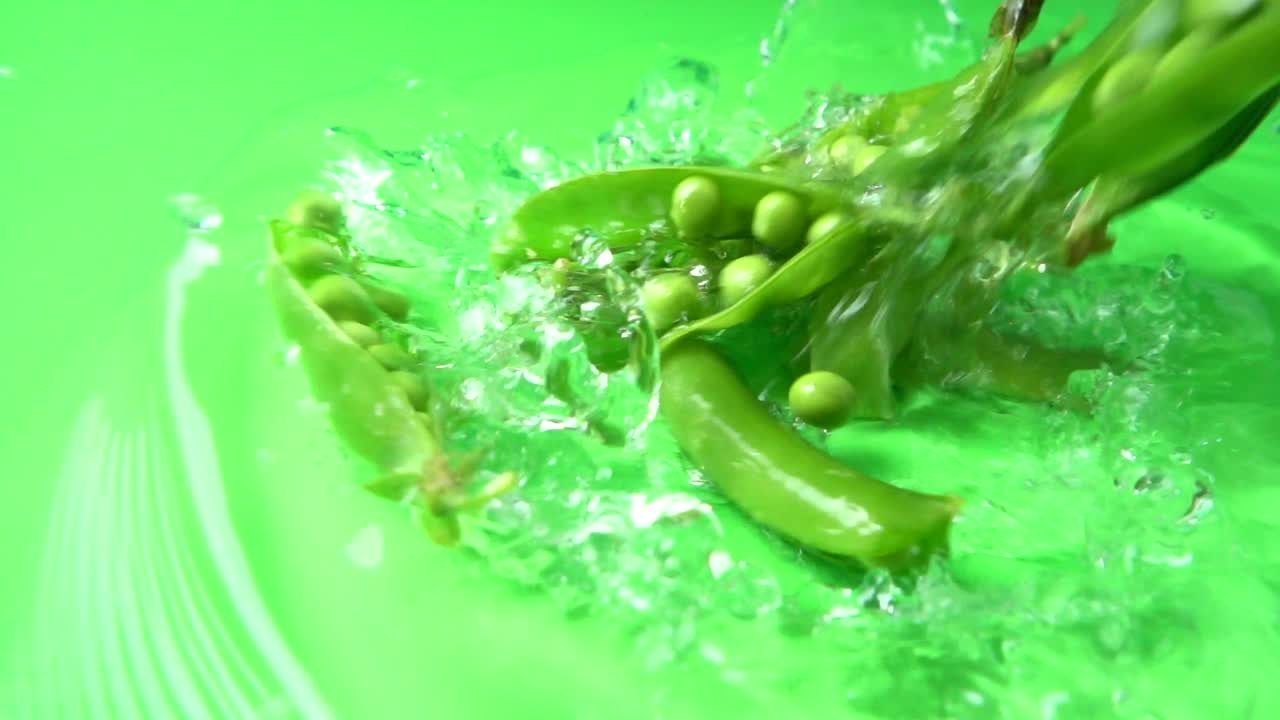 Falling of green peas in water. Slow motion