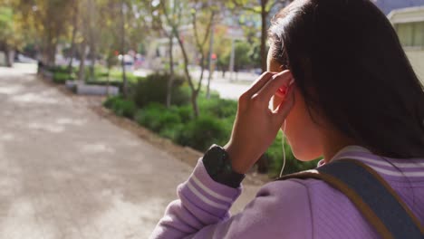 vista lateral de una mujer asiática con auriculares de pie en el parque