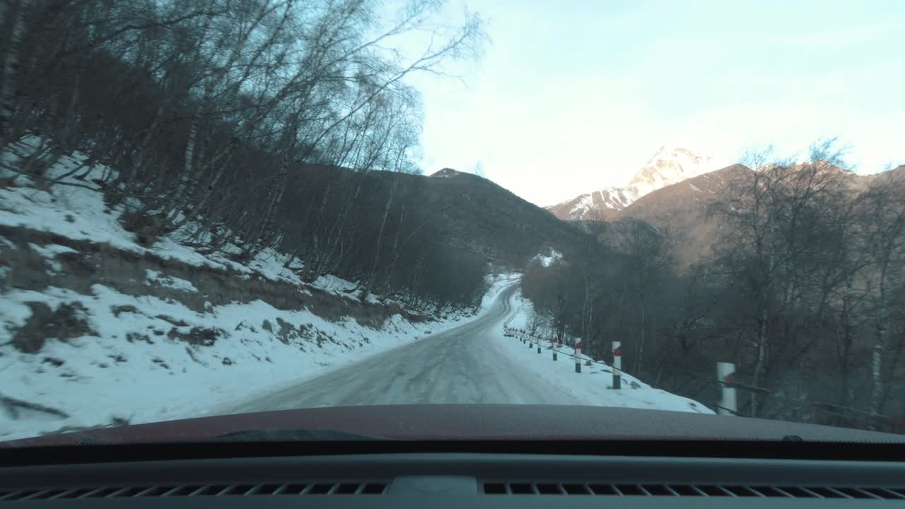 Dangerous driving on mountain edge with the road covered in sleet and ice.