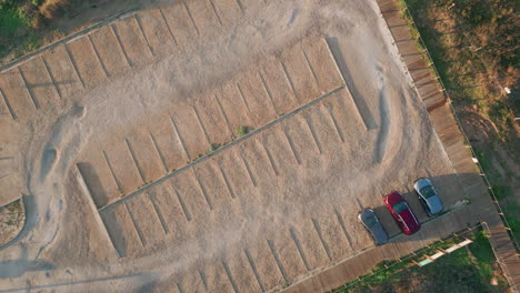 aerial beachside parking lot in sunlight. empty sandy terrain with cars outdoor