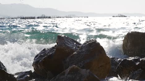 close-up of large rocks on the albanian beach being shattered by the waves of the ionian sea