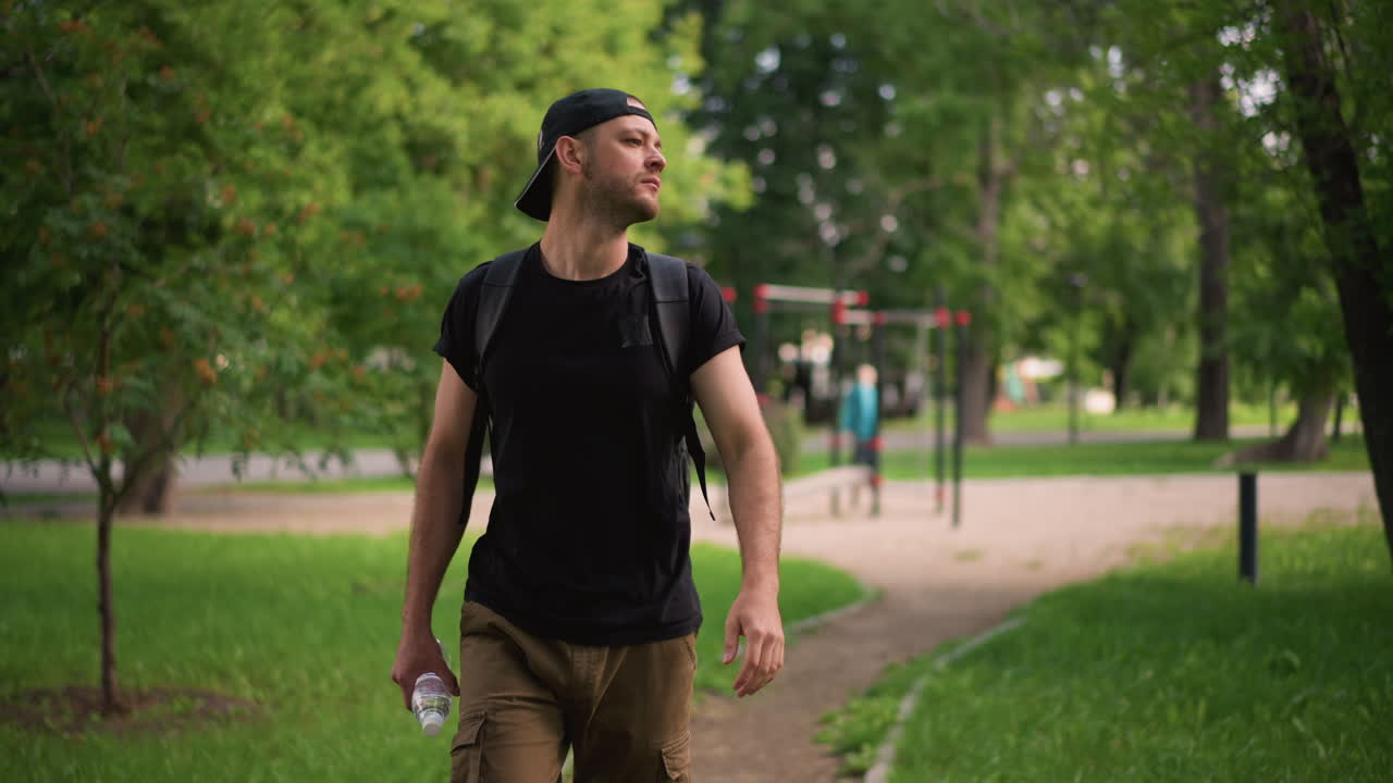 Gentleman In Greenery Adjusts Listening Device, Male Hiker Pauses To Fix His Earphone Amid Natural Scenery, Relaxed Man In Park Carefully Adjusts His Earbud While Appreciating Outdoor Beauty
