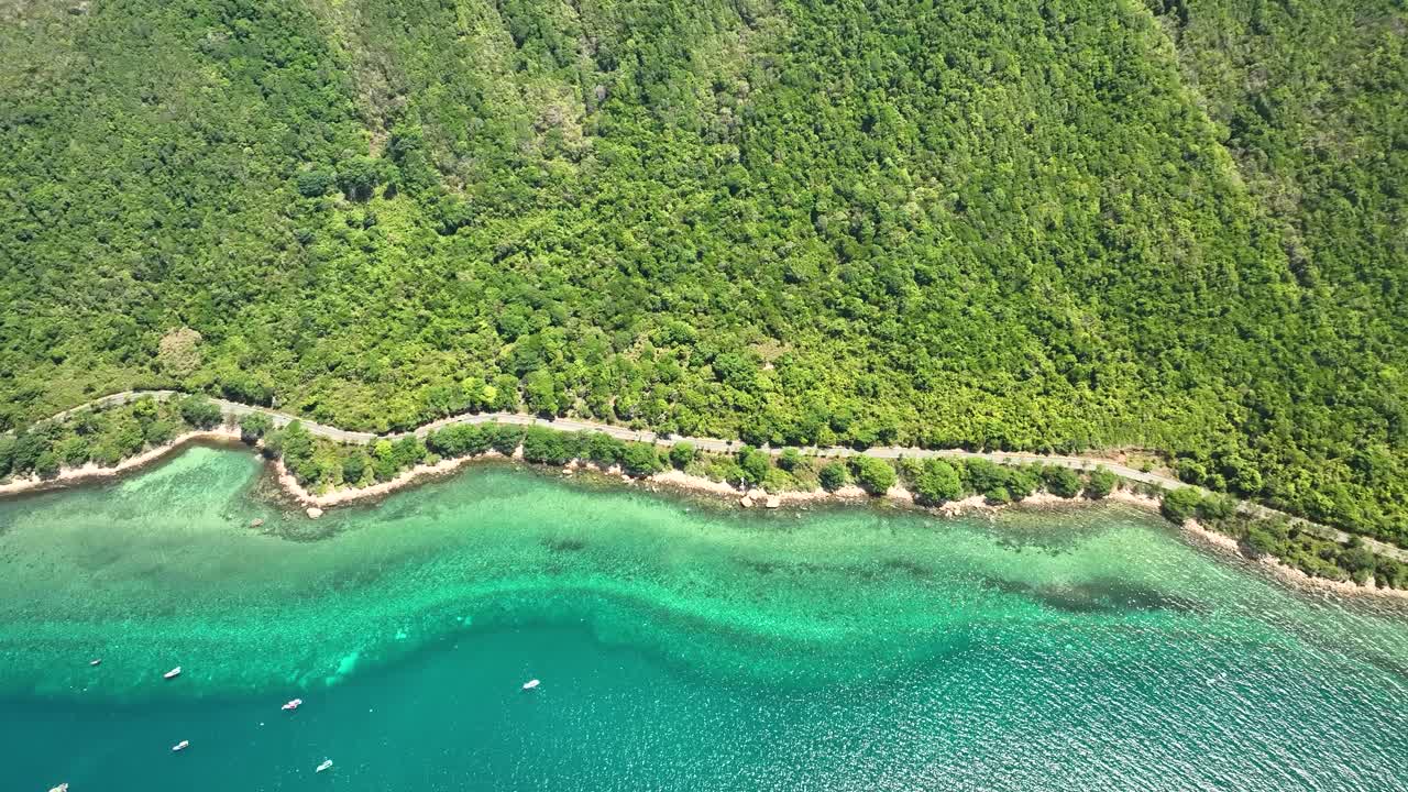 Boats Floating On The Crystal Clear Waters Along The Road In Con Dao Island In Vietnam. - aerial shot