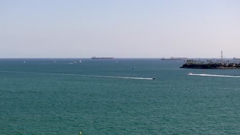 Aerial-tracking-shot-of-Speed-boats-Cruising-by-Kitesurfer-In-Long-Beach-coastline,-California