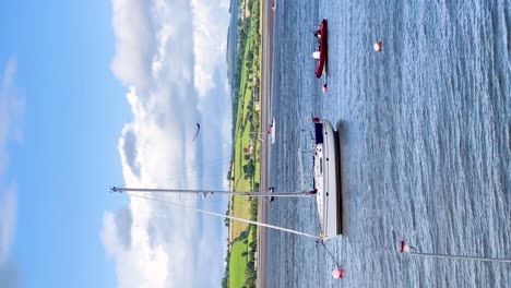 Sunny-Yachting-Escape:-Vertical-Video-of-a-Serene-Day-with-a-Yacht-by-the-Blue-River,-Nestled-Amidst-Green-Hills