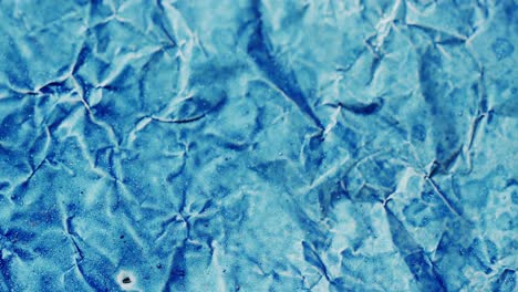 Close-up-of-blue-crumpled-piece-of-paper-in-slow-motion