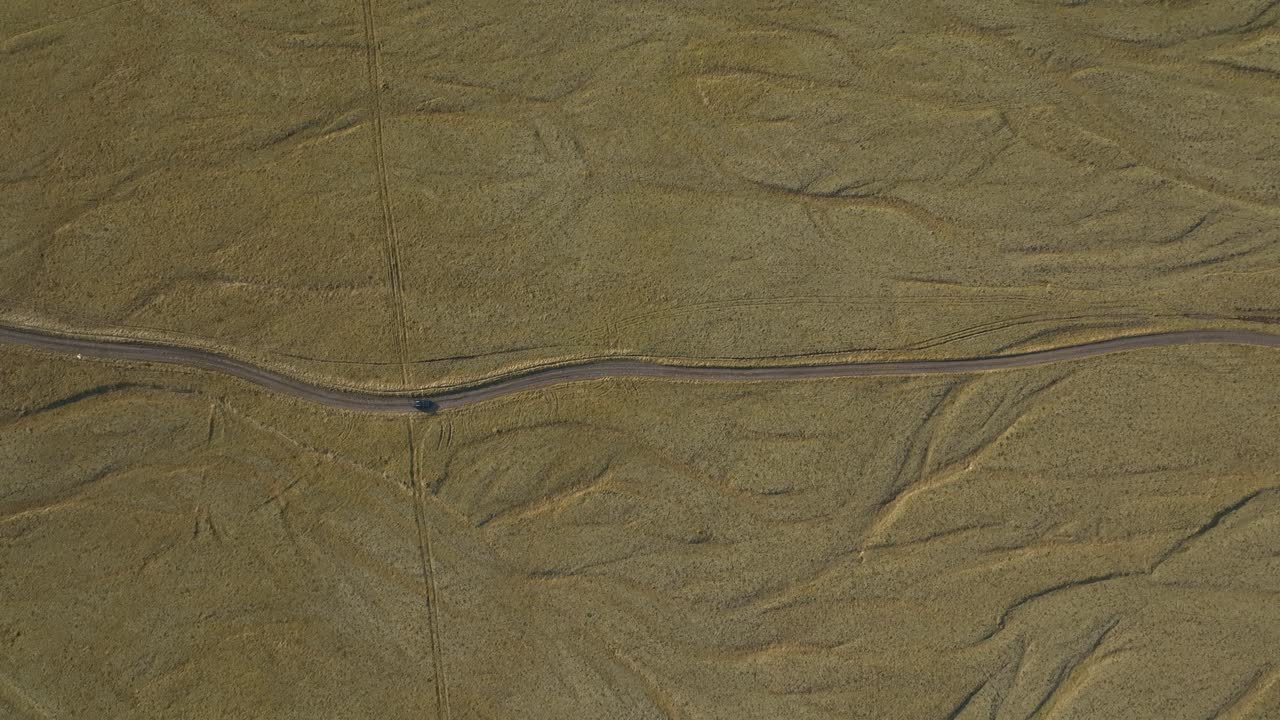 A solitary car travels along a winding road through the vast, barren landscape of northern Iceland, highlighting the region's isolation and untouched nature.
