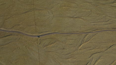 a solitary car travels along a winding road through the vast, barren landscape of northern iceland, highlighting the region's isolation and untouched nature.