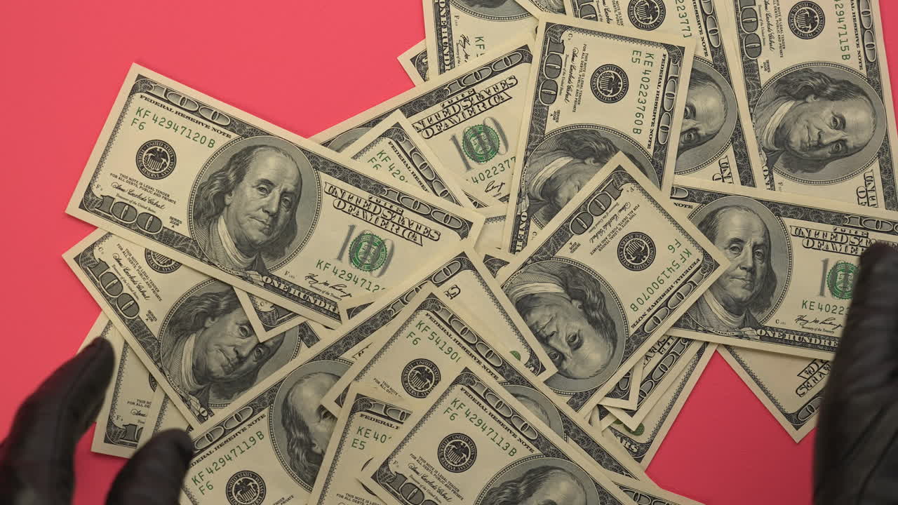 Mani con guanti neri che contano e sistemano banconote da cento dollari