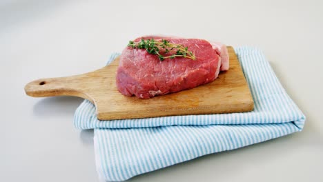 Raw-steak-garnished-with-rosemary-on-chopping-board