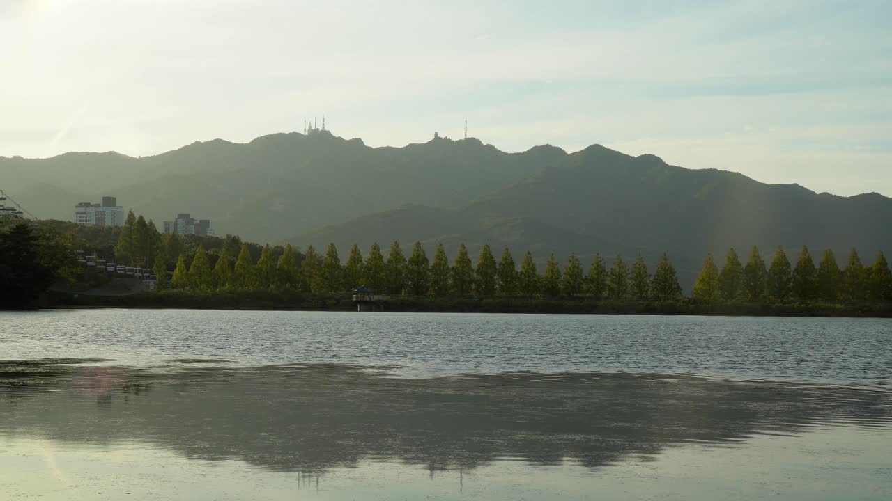 푸른 나무와 높은 산으로 둘러싸인 가을 동안 밝은 흐린 하늘 아래 서울 대공원의 평화로운 호수 - 광각 촬영