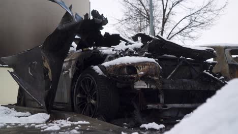 vandalised car arson attack, city crime scene burned vehicle covered in snow