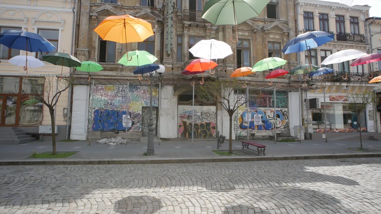 Braila, Romania. April 24 2019 The old central part. Cobbled street. Ancient architecture and multicolored umbrellas hanging in the air. Artistic atmosphere.