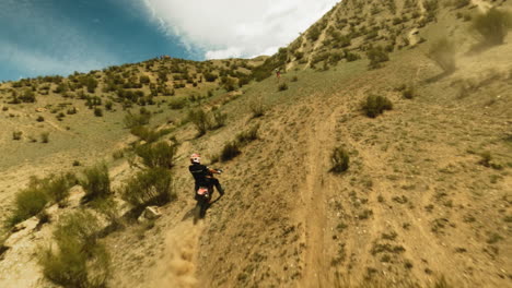 sportsman rides fast motorbike in dusty valley fpv drone. motorcyclist on powerful vehicle competes in offroad racing at summer highland. extreme leisure