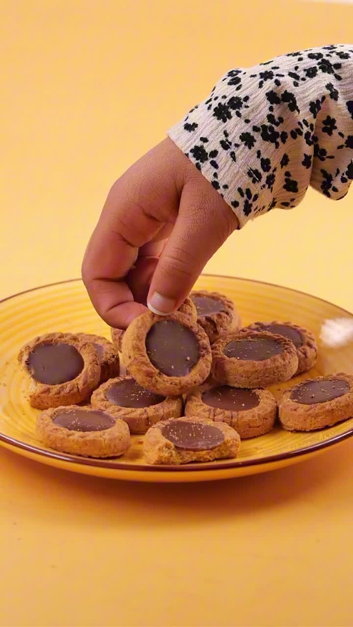 Mano che prende un biscotto al cioccolato da un piatto giallo