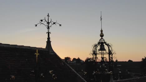 silueta al atardecer del castillo angelus campanario y decoraciones en el techo, saint-emilion en francia