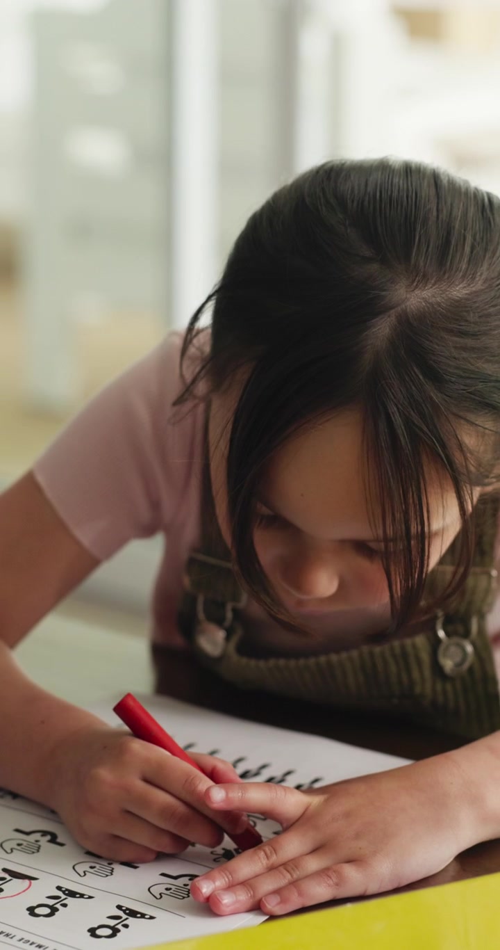 Giovane Ragazza Concentrata nel Completare un Foglio di Esercizi a Casa