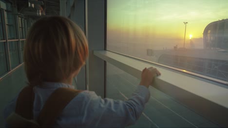 Cerca-De-La-Parte-Trasera-Del-Niño-Pequeño-Parado-En-La-Ventana-Del-Aeropuerto-Y-Mirando-La-Hermosa-Puesta-De-Sol