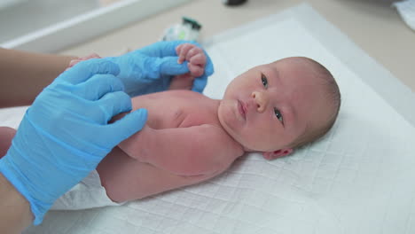 newborn baby at the doctor. doctor checks infant's health after the birth in clinic. cute toddler lying on hospital table while medical worker doing general check up.
