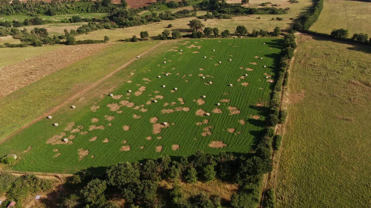 Aerial View of Hay Bales in patchy green field