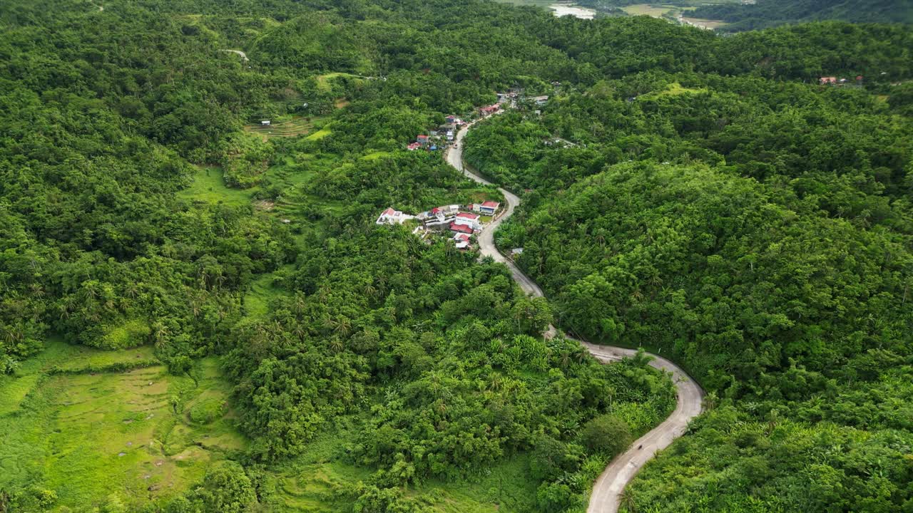 Picturesque aerial view of serpentine roads along a lush hillside village in the tropical province Catanduanes, Philippines