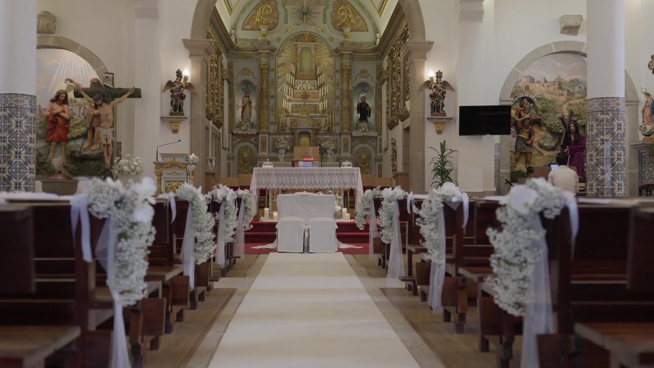 Navata della chiesa e panche decorate con fiori bianchi e nastri, pronte per un matrimonio religioso o un evento speciale