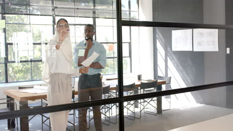 brainstorming and writing on glass wall, business professionals discussing project in office