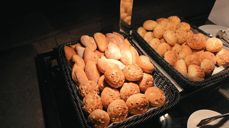 Different kinds of mini bread rolls are displayed in warm light
