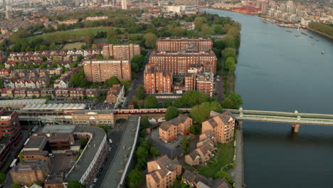 Toma-Aérea-Junto-Al-Tren-De-La-Línea-District-Pasando-Por-El-Río-Támesis-En-El-Puente-Ferroviario-Fulham-Putney