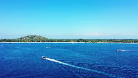 Gili-Island,-Speedboats-Swiftly-Sailing-Towards-The-Lush-Island-On-A-Bright-Sunny-Weather---A-Wonderful-Summer-Adventure---Aerial-Drone-Shot