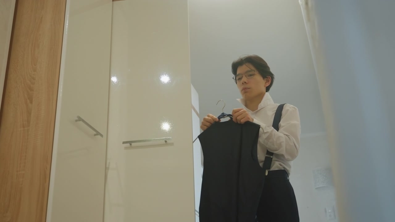 Man adjusting suspenders at closet doorway firm grip on jacket, smooth fabric, focused gaze, quick precise movements, readying for presentation, overhead lights, reflective surfaces, modern corridor