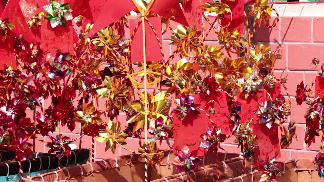 Vibrant pinwheels in red and gold adorn a brick wall, creating a festive display.