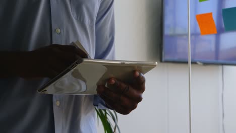 Mid-section-of-young-black-businessman-working-on-digital-tablet-in-a-modern-office-4k