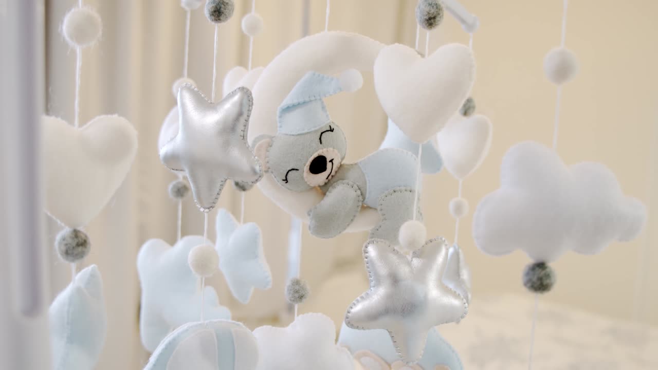 어린이의 부드러운 장난감은 요람 침대 위에서 원으로 회전합니다. 가까이 가십시오.