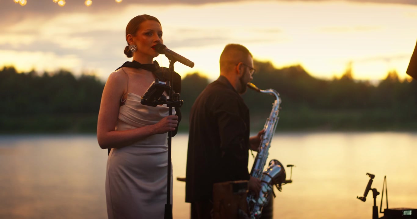 Sängerin und Saxophonist live am Wasser bei Sonnenuntergang