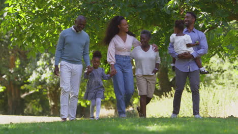 Mehrgenerationenfamilie-Genießt-Gemeinsam-Einen-Spaziergang-Auf-Dem-Land-Und-Schaukelt-Ihre-Enkelin