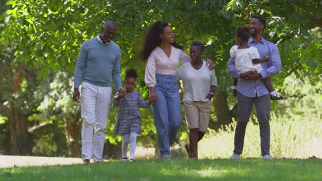 multi-generation family enjoying walk in countryside together swinging granddaughter