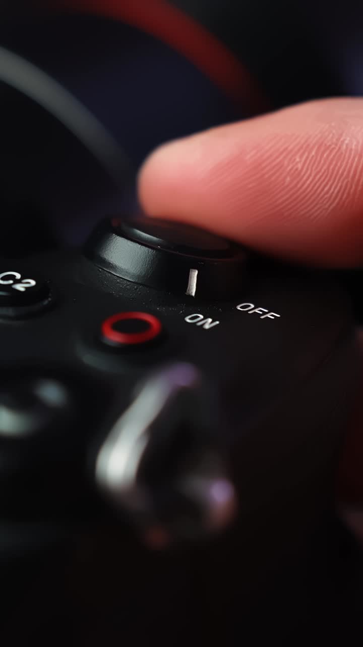 Macro shot of a finger sliding a mirrorless camera power lever to ON, activating the controls and getting ready to film with shallow depth of field