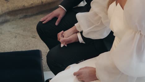 bride and groom seated holding hands during wedding ceremony